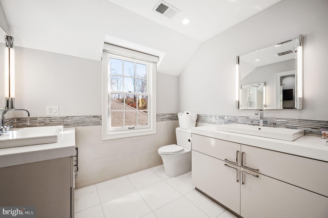 bathroom featuring vanity, visible vents, vaulted ceiling, tile patterned floors, and toilet