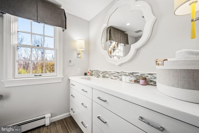 bathroom with a baseboard heating unit, backsplash, wood finished floors, and a wealth of natural light