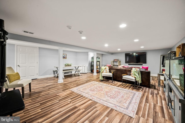 living room with recessed lighting, visible vents, baseboards, and wood finished floors