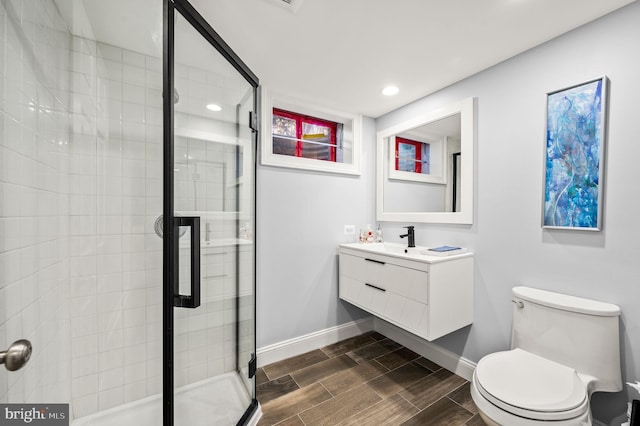 bathroom featuring wood finish floors, baseboards, a stall shower, and vanity