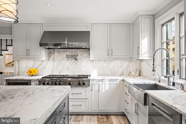 kitchen featuring ventilation hood, tasteful backsplash, appliances with stainless steel finishes, and a sink