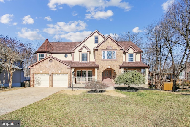 view of front facade featuring stucco siding, a front lawn, covered porch, concrete driveway, and brick siding