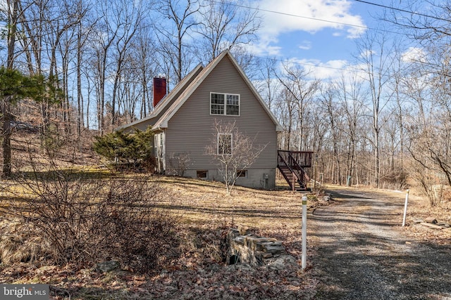 view of side of home with stairway and a chimney