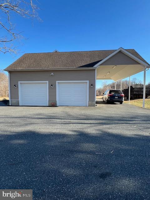 exterior space featuring a garage, a carport, and an outdoor structure