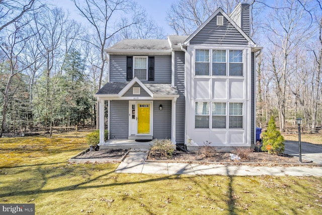 traditional home featuring a front lawn and a chimney