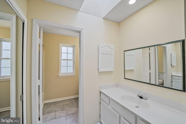 bathroom featuring tile patterned floors, toilet, vanity, and baseboards