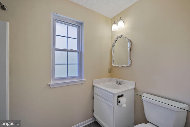 half bathroom featuring a textured ceiling, toilet, vanity, and baseboards