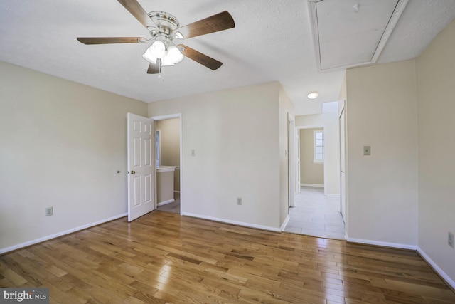 unfurnished room featuring baseboards, attic access, and hardwood / wood-style flooring