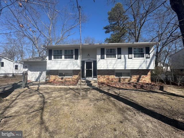 split foyer home with brick siding, an attached garage, driveway, and fence