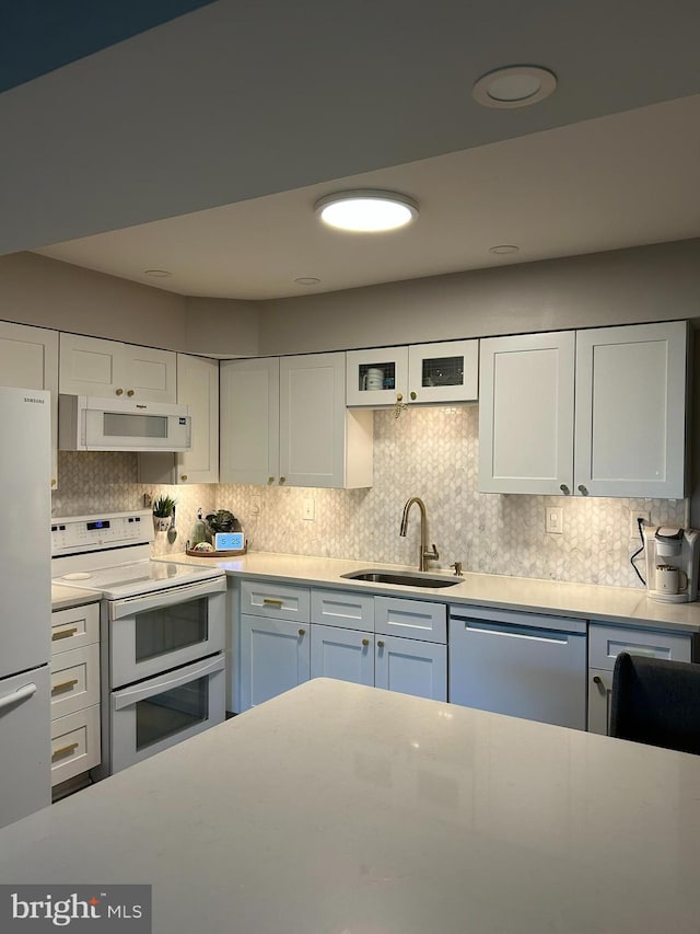 kitchen with white cabinetry, white appliances, light countertops, and a sink