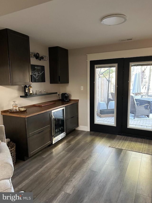 bar with visible vents, beverage cooler, dark wood finished floors, french doors, and a dry bar