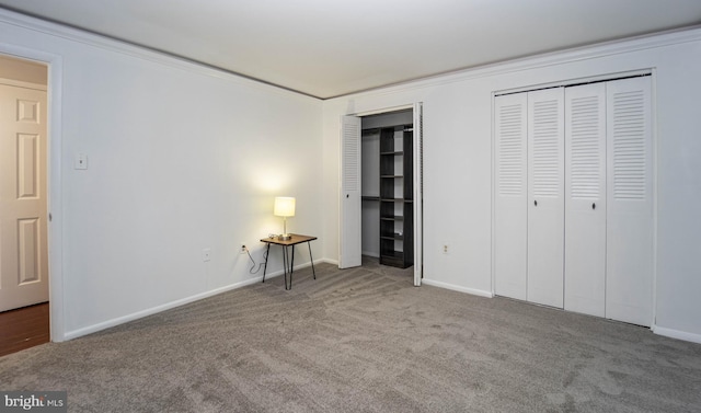 unfurnished bedroom with baseboards, two closets, and carpet