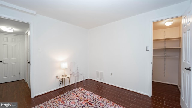 unfurnished bedroom featuring wood finish floors, visible vents, baseboards, and a spacious closet