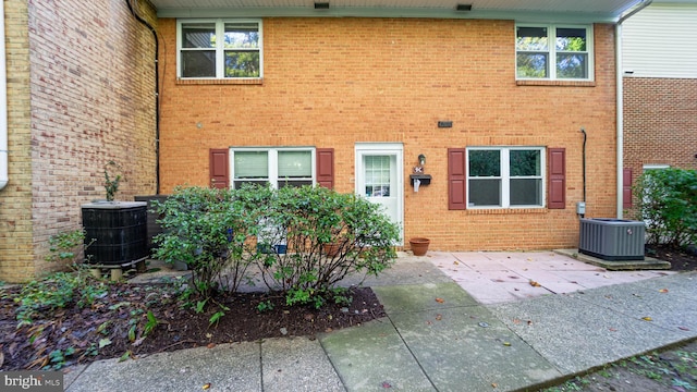 property entrance featuring a patio, cooling unit, and brick siding