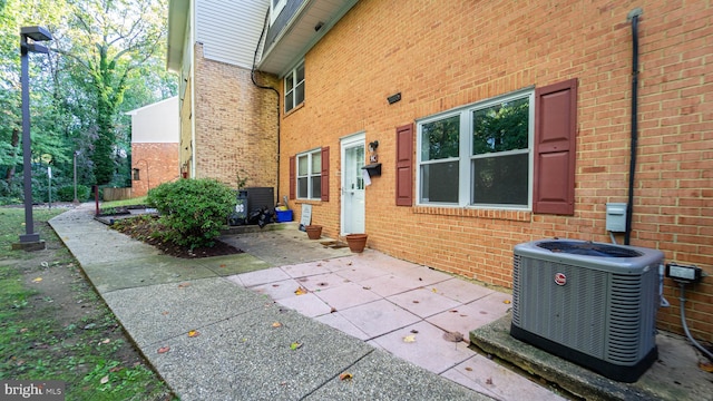 property entrance featuring a patio, central air condition unit, and brick siding