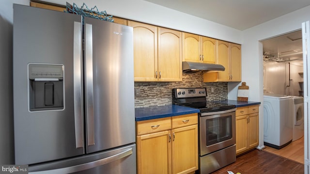 kitchen featuring dark countertops, backsplash, dark wood-type flooring, under cabinet range hood, and stainless steel appliances