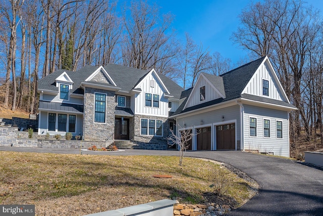 view of front facade with stone siding, board and batten siding, driveway, and a front yard