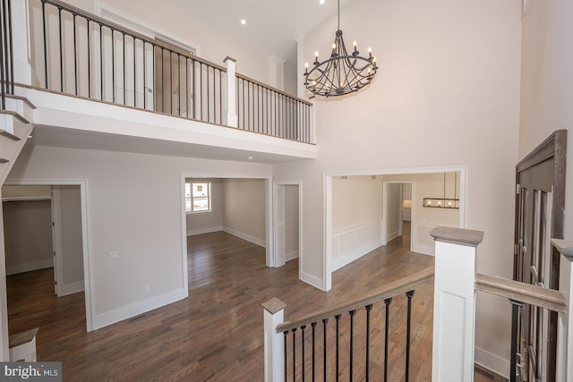 foyer featuring baseboards, wood finished floors, a notable chandelier, and a towering ceiling