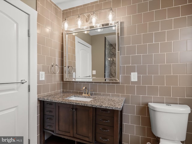 bathroom with vanity, tile walls, toilet, and backsplash