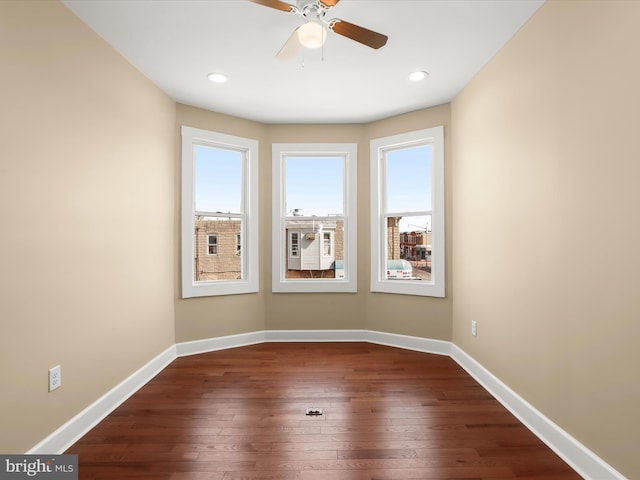 spare room featuring a wealth of natural light, dark wood-type flooring, and baseboards