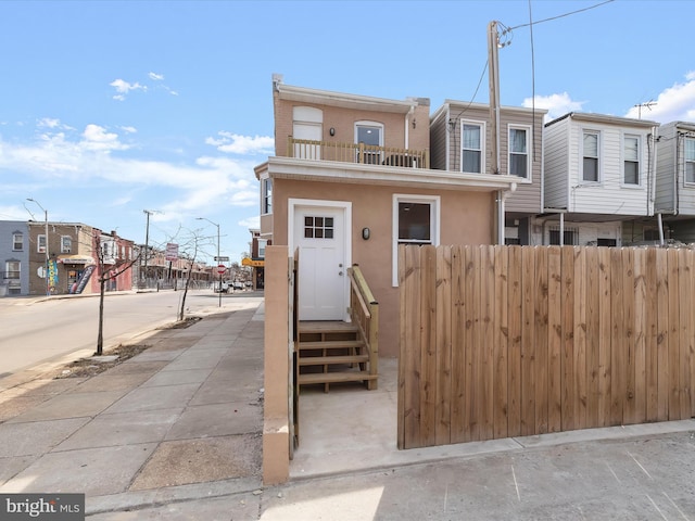 townhome / multi-family property with stucco siding, a residential view, and fence