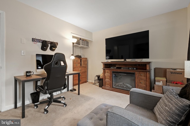 carpeted home office with baseboards and a glass covered fireplace