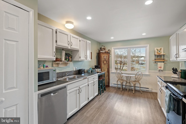 kitchen with white microwave, dishwasher, baseboard heating, white cabinetry, and a sink