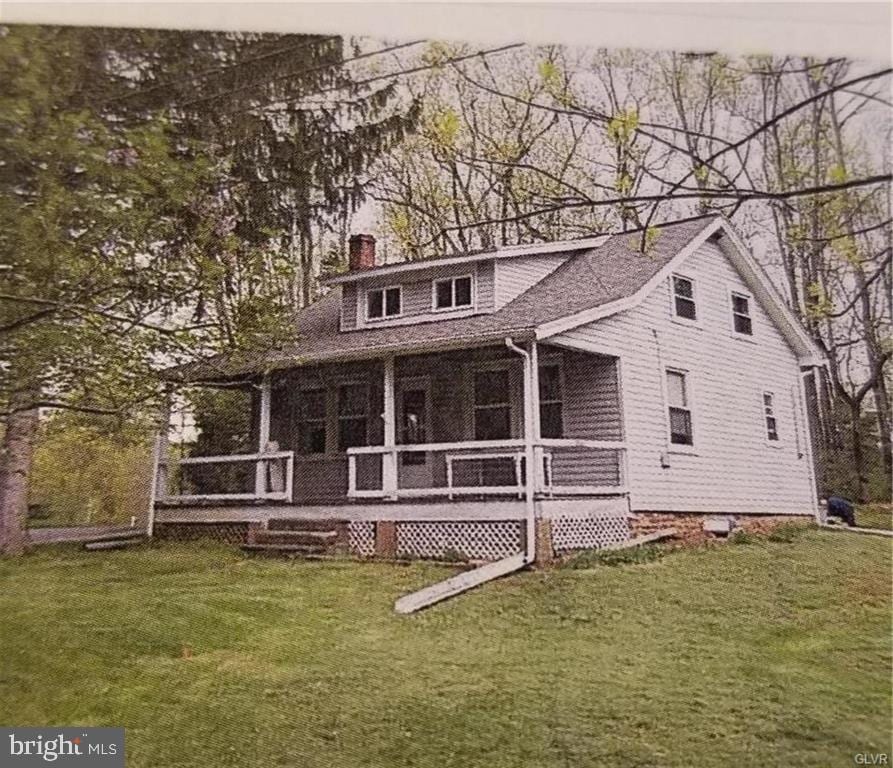 view of front of property featuring a front lawn, a sunroom, and a chimney