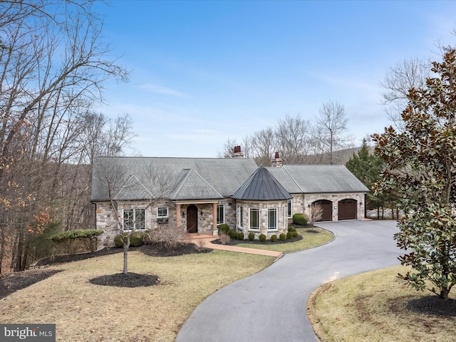 view of front of property featuring a front lawn, driveway, a standing seam roof, an attached garage, and metal roof