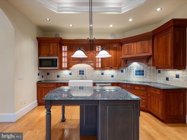 kitchen with black appliances, light wood-style flooring, a sink, backsplash, and a kitchen island