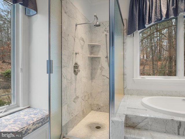 bathroom featuring a garden tub and a marble finish shower