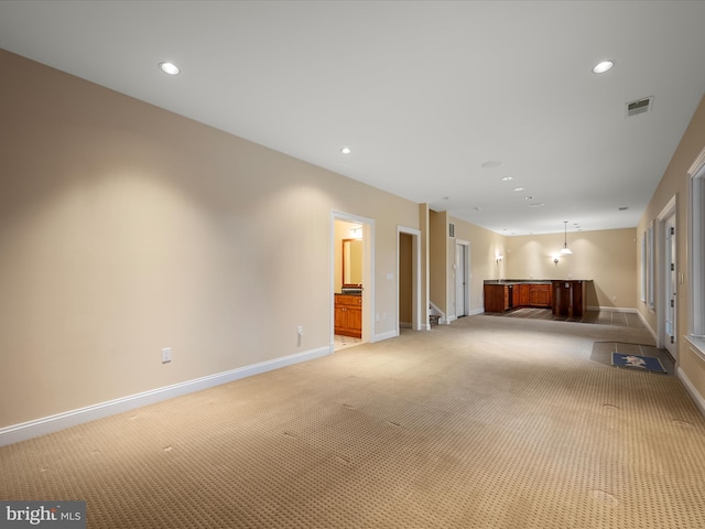 unfurnished living room featuring visible vents, light colored carpet, and baseboards