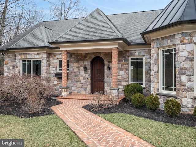 view of exterior entry featuring metal roof, roof with shingles, and a standing seam roof