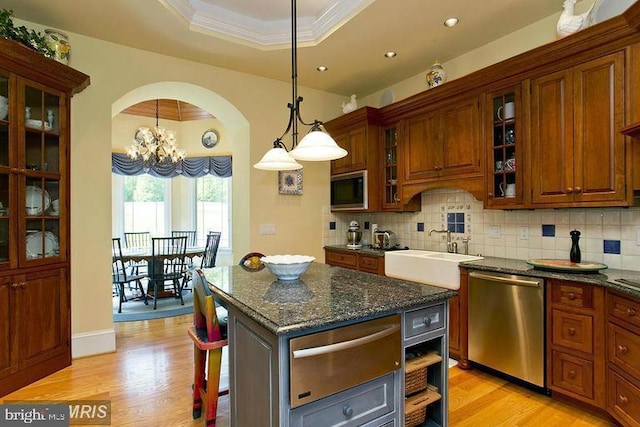 kitchen with a sink, decorative backsplash, light wood-style floors, appliances with stainless steel finishes, and a warming drawer