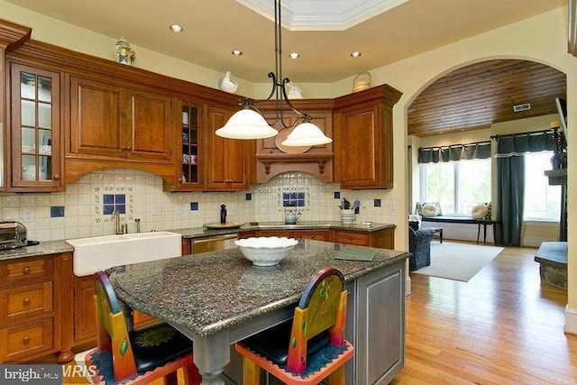 kitchen with tasteful backsplash, brown cabinets, arched walkways, and a sink