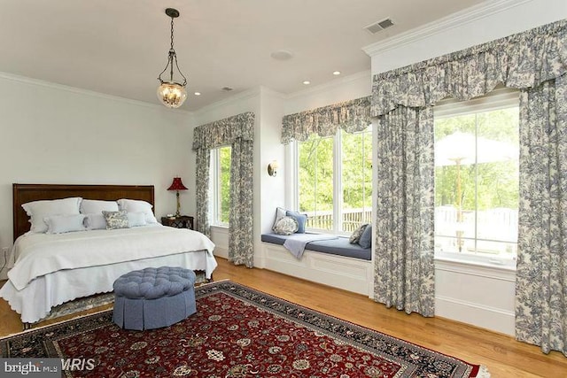 bedroom featuring a chandelier, visible vents, crown molding, and wood finished floors