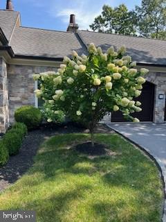 view of home's exterior featuring stone siding, a lawn, an attached garage, and driveway