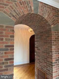 interior space featuring brick ceiling, visible vents, brick wall, wood finished floors, and arched walkways