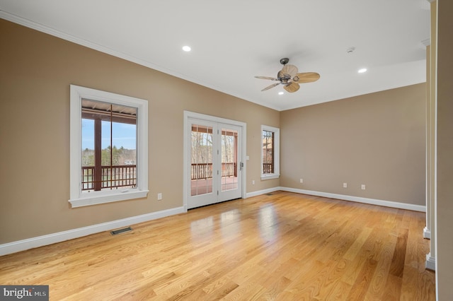 spare room with light wood-style flooring, visible vents, baseboards, and ornamental molding