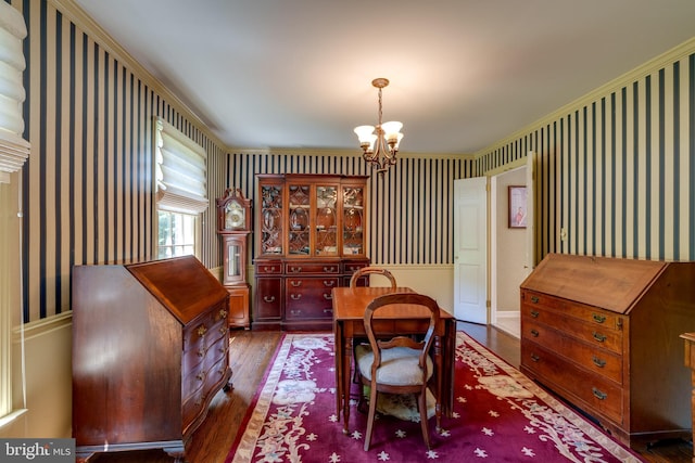 dining area featuring a chandelier, wood finished floors, crown molding, and wallpapered walls