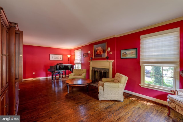 living area featuring ornamental molding, a fireplace, baseboards, and wood finished floors