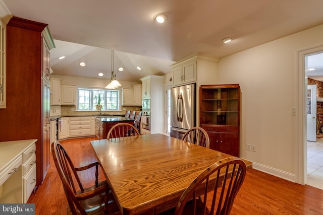 dining space featuring light wood finished floors, recessed lighting, lofted ceiling, and baseboards