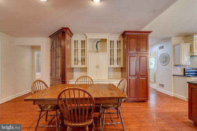 dining room featuring visible vents, baseboards, and light wood finished floors