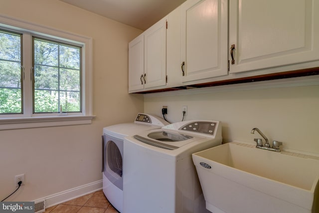 washroom with visible vents, a sink, washer and dryer, cabinet space, and light tile patterned floors