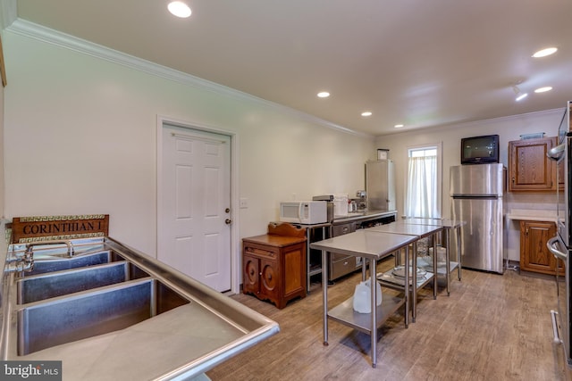 kitchen featuring white microwave, crown molding, freestanding refrigerator, and light wood-style floors