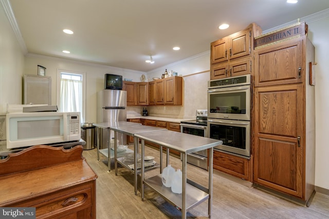 kitchen featuring ornamental molding, light wood-style floors, appliances with stainless steel finishes, brown cabinetry, and light countertops