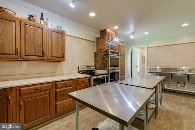 kitchen featuring stainless steel countertops, brown cabinets, appliances with stainless steel finishes, and light wood-type flooring