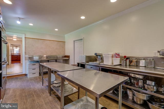 kitchen featuring recessed lighting, stainless steel countertops, wood finished floors, and crown molding