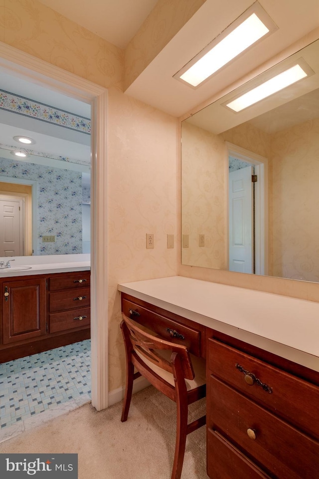 office area featuring built in study area, wallpapered walls, light colored carpet, and a sink