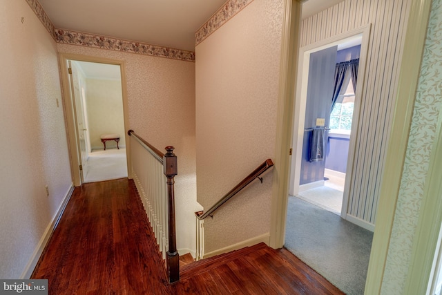 corridor with wood finished floors, an upstairs landing, and baseboards